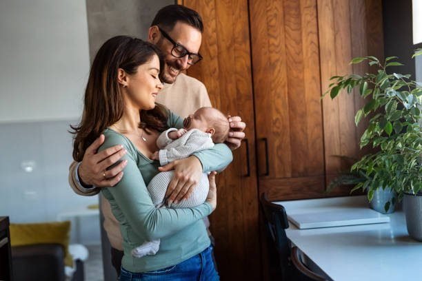 A mom and dad together holding their newborn baby, showing partner support during breastfeeding.