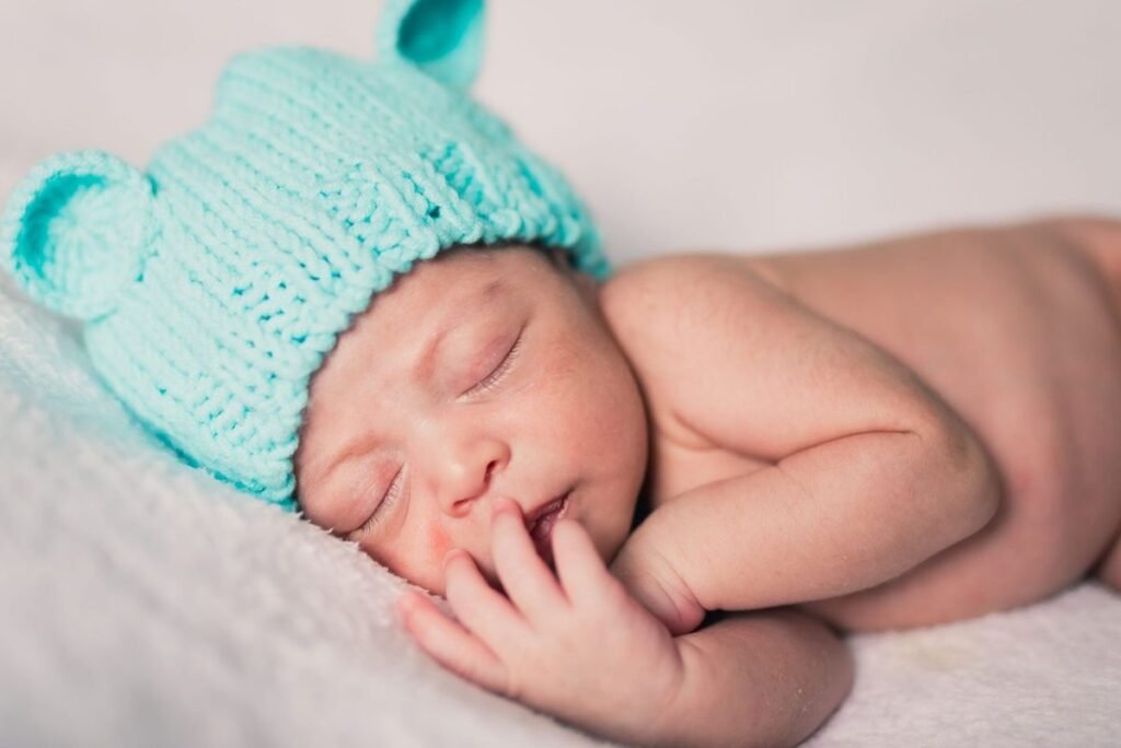 A sleeping newborn baby in a teal knit hat.