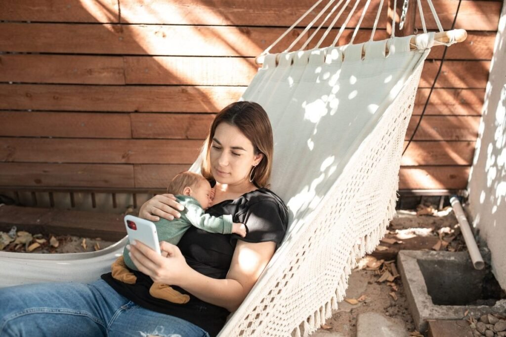 A mother breastfeeding her baby while relaxing in an outdoor hammock.